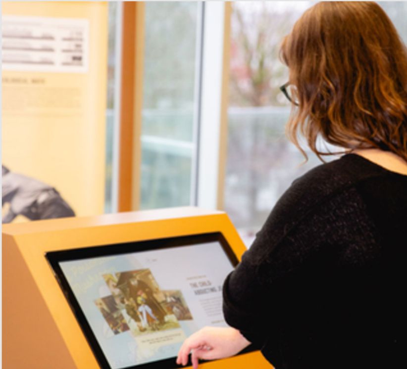 A visitor using one of the exhibit's touchscreen kiosks