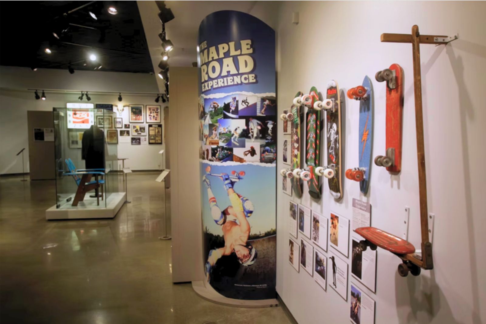 The Maple Road Experience gallery: a tall printed column with the exhibit title beside a wall of vintage skateboards and photographs