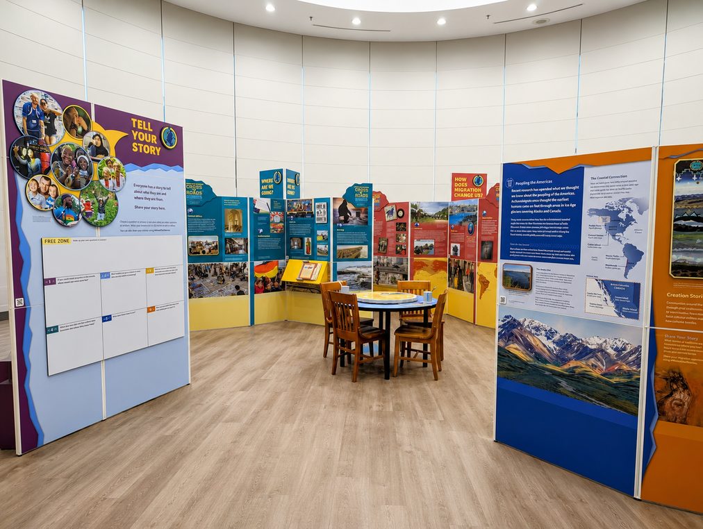 World on the Move installed in a library reading room: curved graphic panels around a round table with chairs